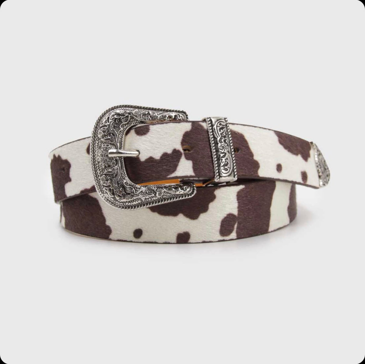 Cinturón La tiendita de Carlita con estampado animal print de vaca, cuero sintético y hebilla plateada grabada