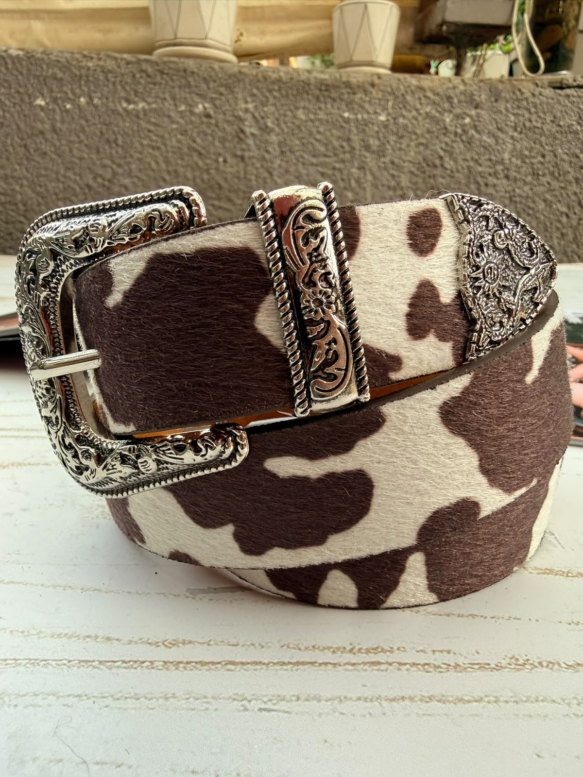 Cinturón La tiendita de Carlita de simil cuero con estampado animal print de vaca café y hebilla plateada grabada